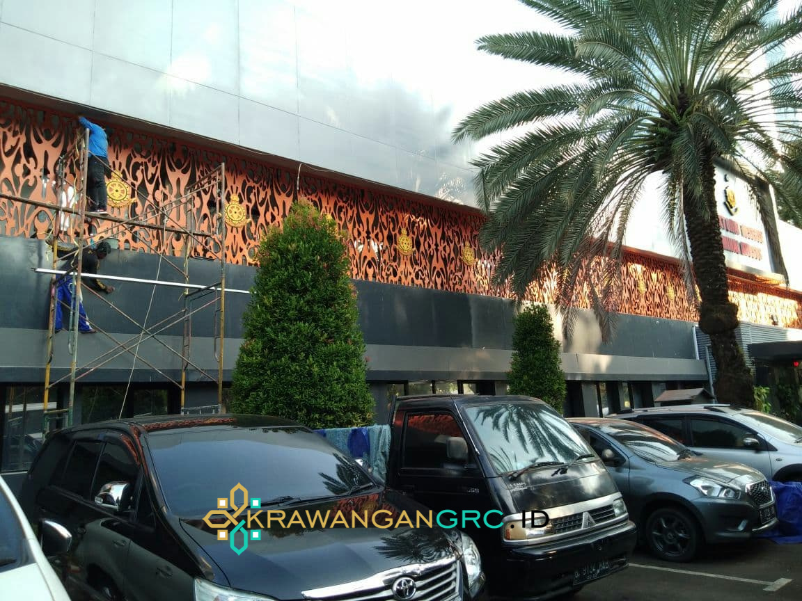 Tim KrawanganGRC.id memasang panel krawangan GRC warna oranye bermotif sulur pada fasad gedung Polri
